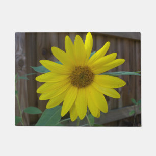 Yellow Sunflower near a brown fence on a Doormat