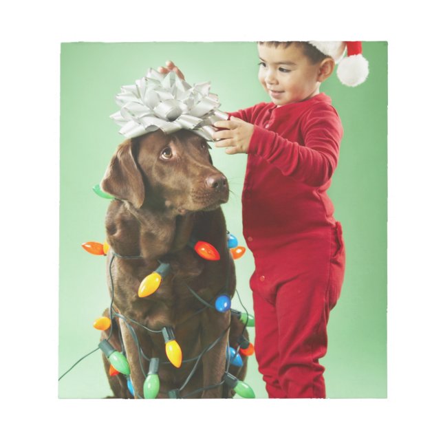 Young boy wrapping Christmas lights around a dog Notepad (Front)
