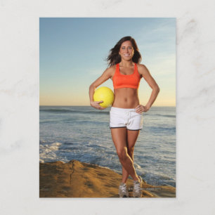 young fit pretty female holding a volleyball at postcard