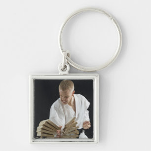 Young man breaking boards with karate chop on key ring