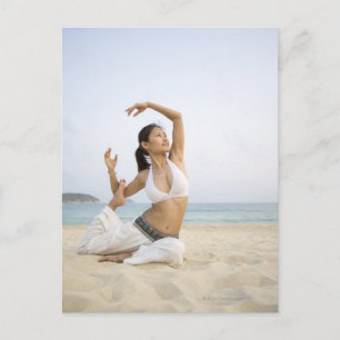 Young woman doing yoga on the beach postcard