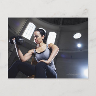 Young woman exercising with dumbbell postcard
